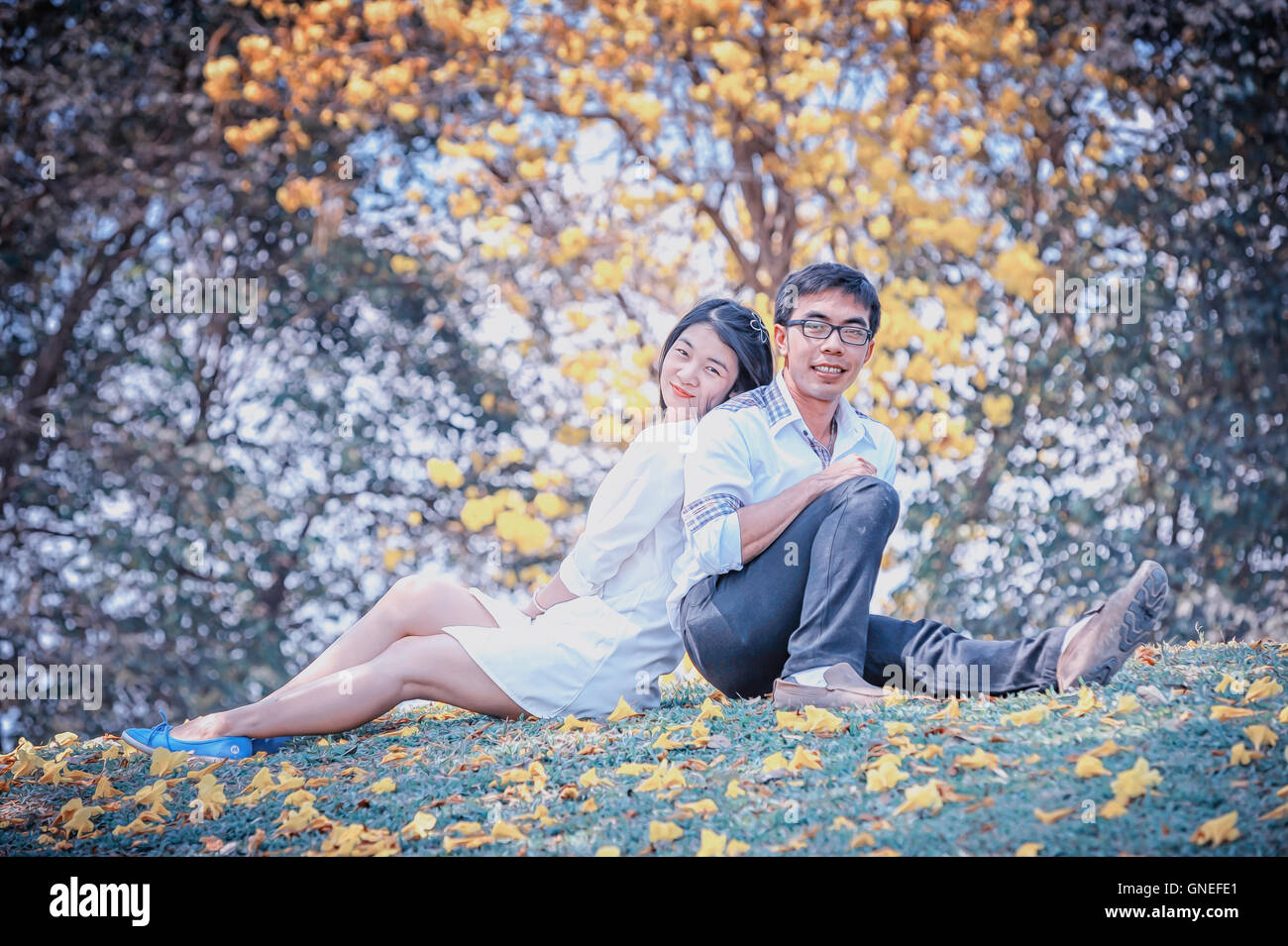 portrait of asia lovely young couple back-to-back under tree Stock Photo