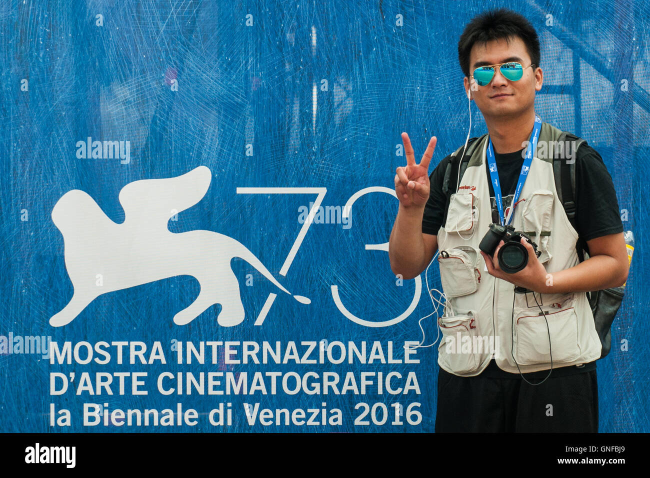 Venice, Italy. 30th August, 2016. A journalist stands in front of a sign of the 73rd Venice Film Festival. Credit:  Simone Padovani / Awakening / Alamy Live News Stock Photo