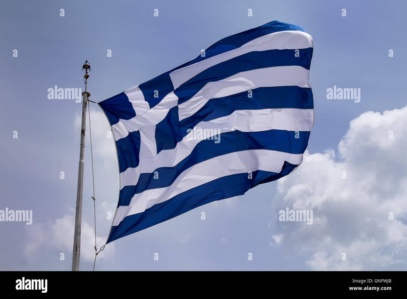 Greek flag blowing in the wind. Cloudy sky in the background. Stock Photo