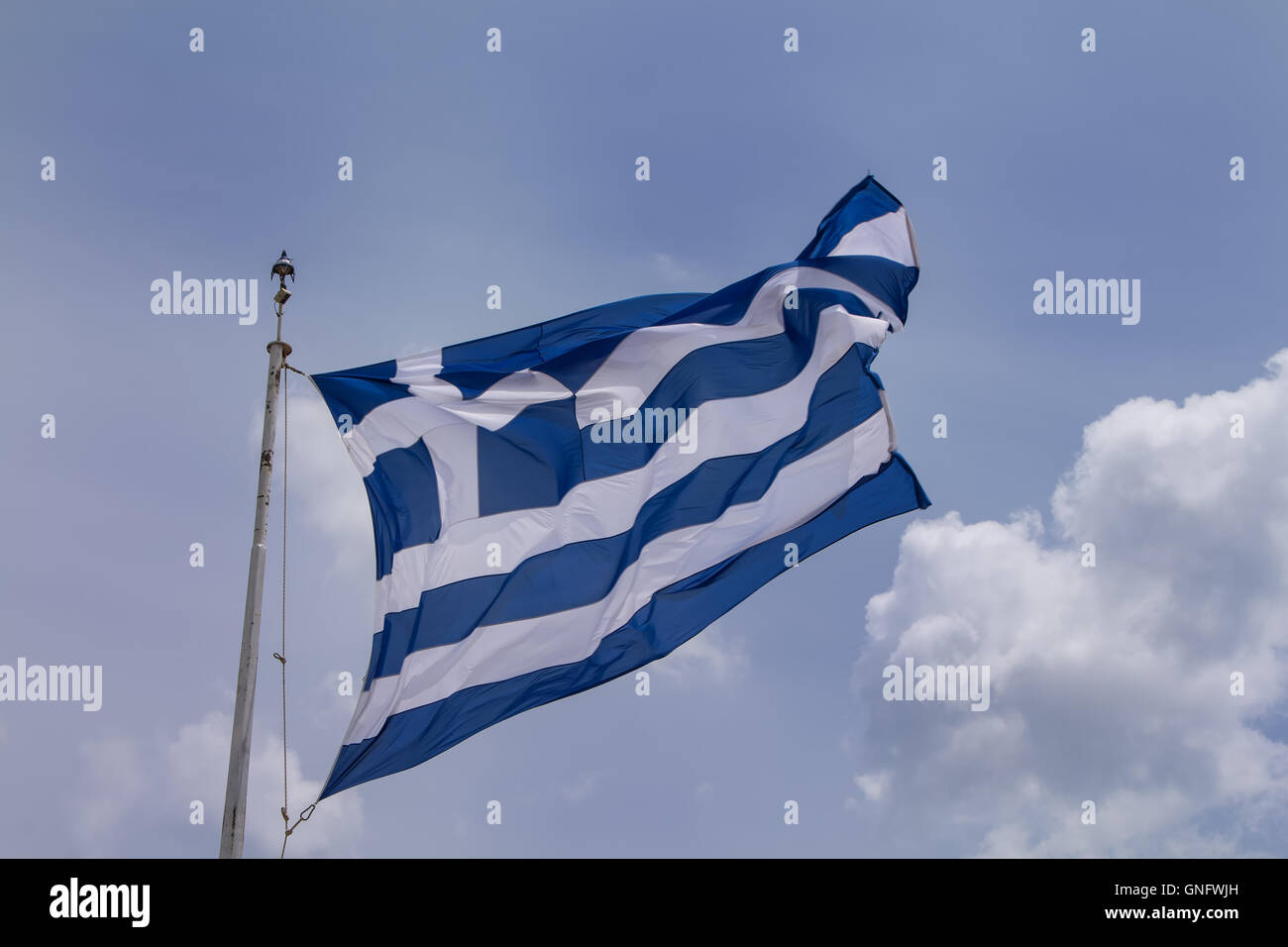 Greek flag blowing in the wind. Cloudy sky in the background. Stock Photo