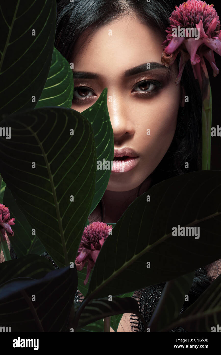 Closeup portrait of a beautiful Asian woman with plant leaves. Stock Photo