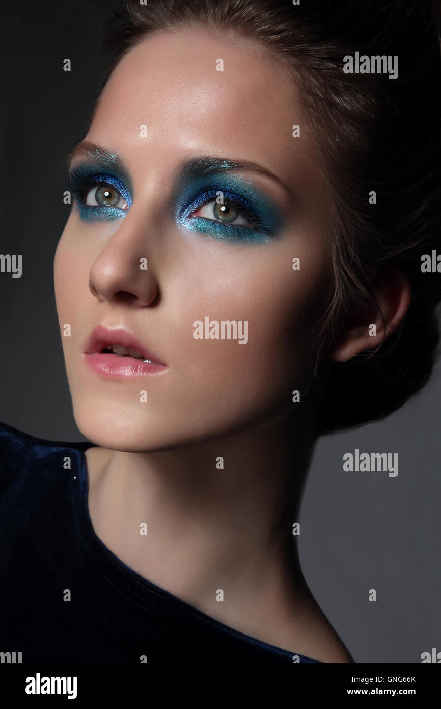 Young beautiful woman with fancy retro make-up. Bright blue eye shadow. Face close-up. Stock Photo