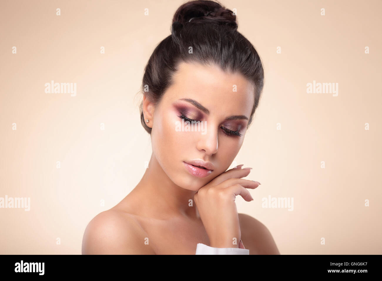 Portrait of beautiful woman touching her face, isolated on beige background. Stock Photo