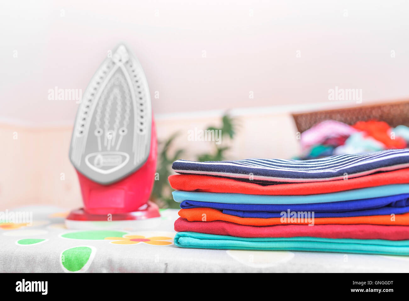 Iron and ironed clothes on an ironing board. Stock Photo
