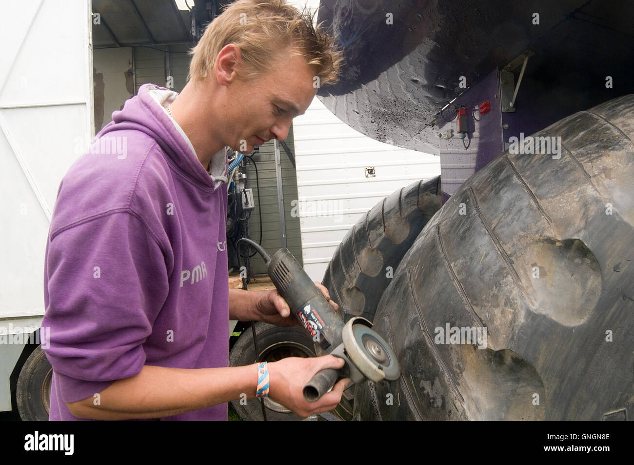 mechanic cutting the treads on a tractor puller before a run with an angle grinder Stock Photo