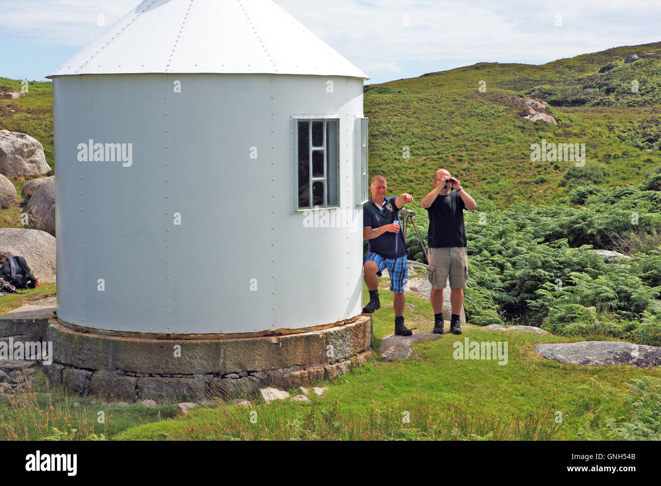 Men looking and pointing at the view from the disused lighthouse signal station, Isle of Erraid, Inner Hebrides of Scotland Stock Photo