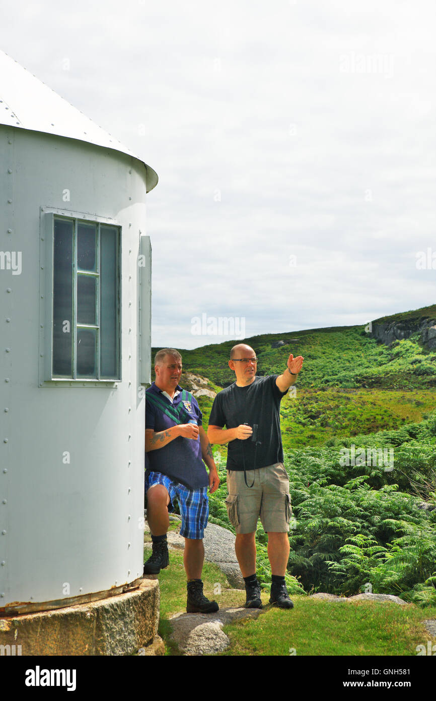 Men discussing the view at the disused lighthouse signal station on the Isle of Erraid in the Inner Hebrides of Scotland Stock Photo