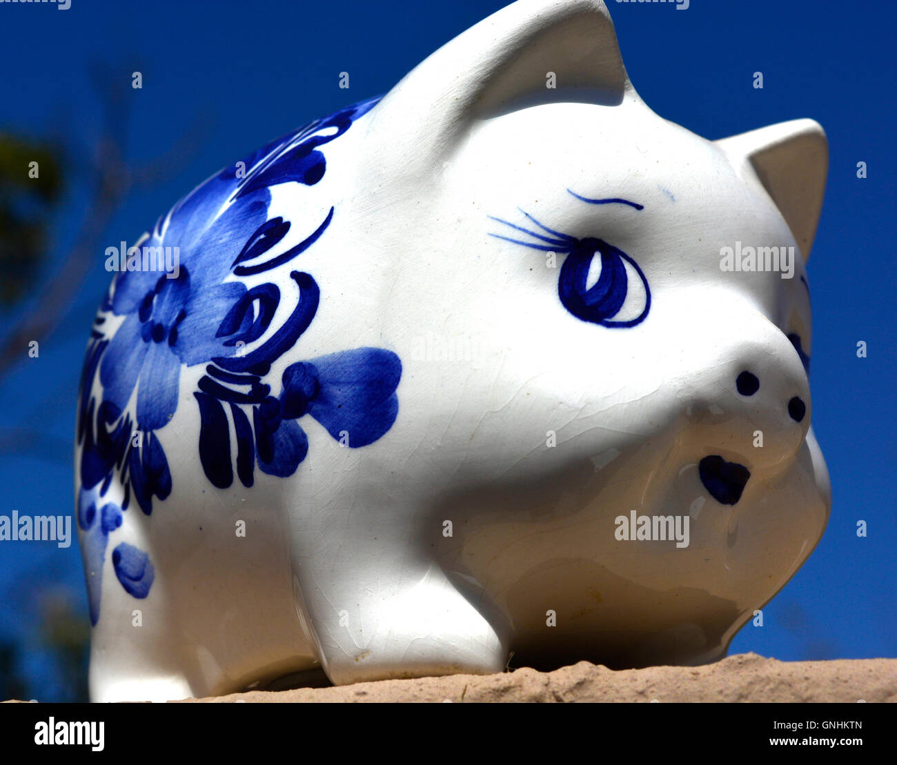 White en blue ceramic savings piggy bank on blue sky background looking right diagonally. Stock Photo