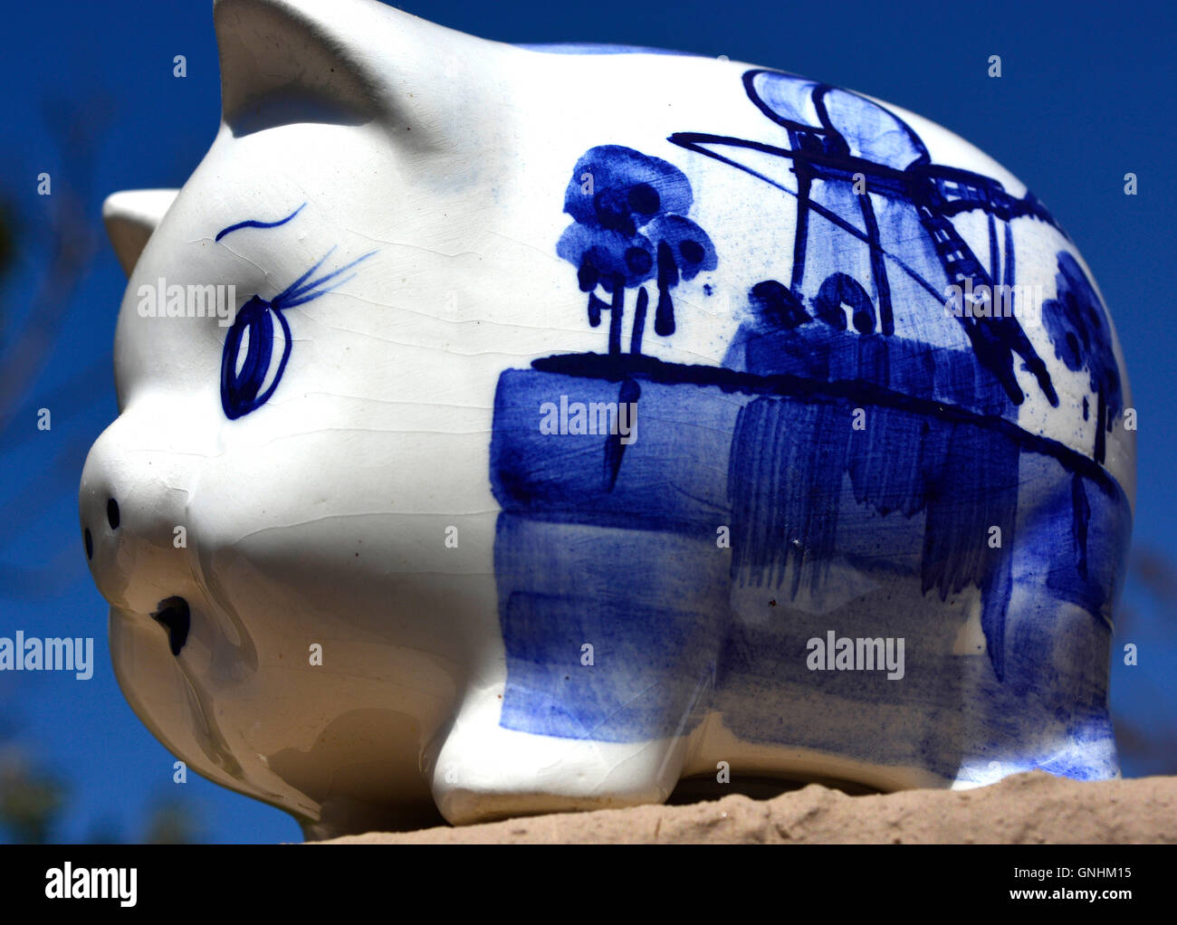 White en blue ceramic savings piggy bank on blue sky background looking ...