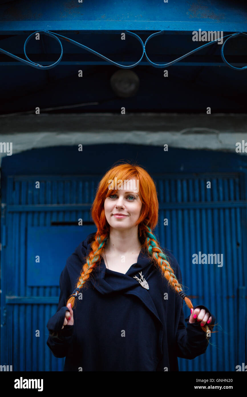 Funny bright young woman smiling. Colored red braided hair. Stock Photo