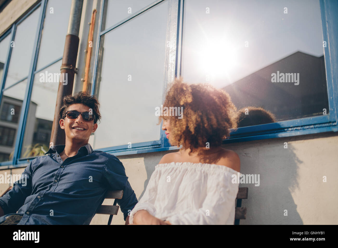 Shot of young man and woman sitting outdoors and talking. Young couple spending time together. Stock Photo