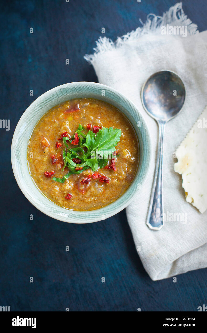 Red Lentil Soup topped with sun dried tomato and arugula in ceramic