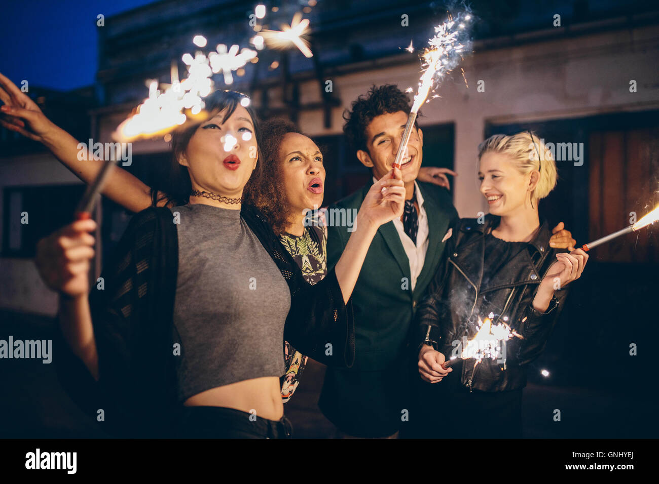 Group of friends enjoying out with sparklers on city street. Young people enjoying new years eve with fireworks. Stock Photo