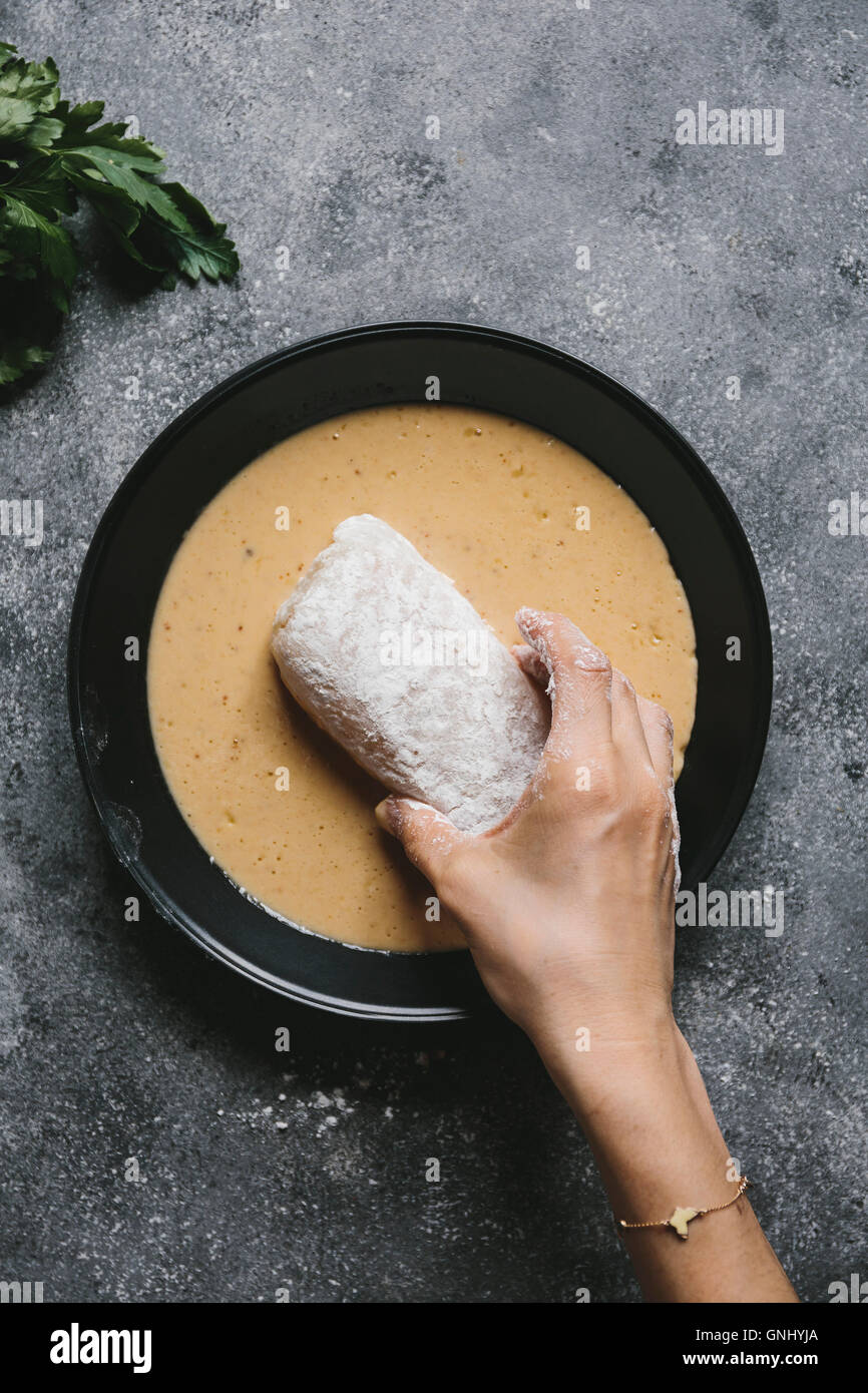 Step2/4 A woman is dipping flour coated fish fillet into an egg mixture