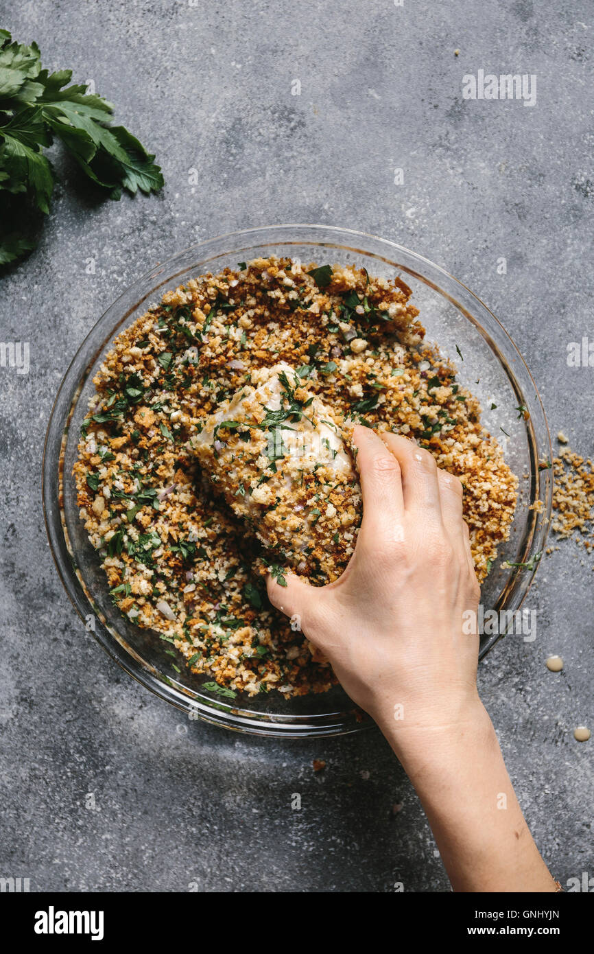 Step 3/4 A woman is photographed as she is coating a fish fillet with