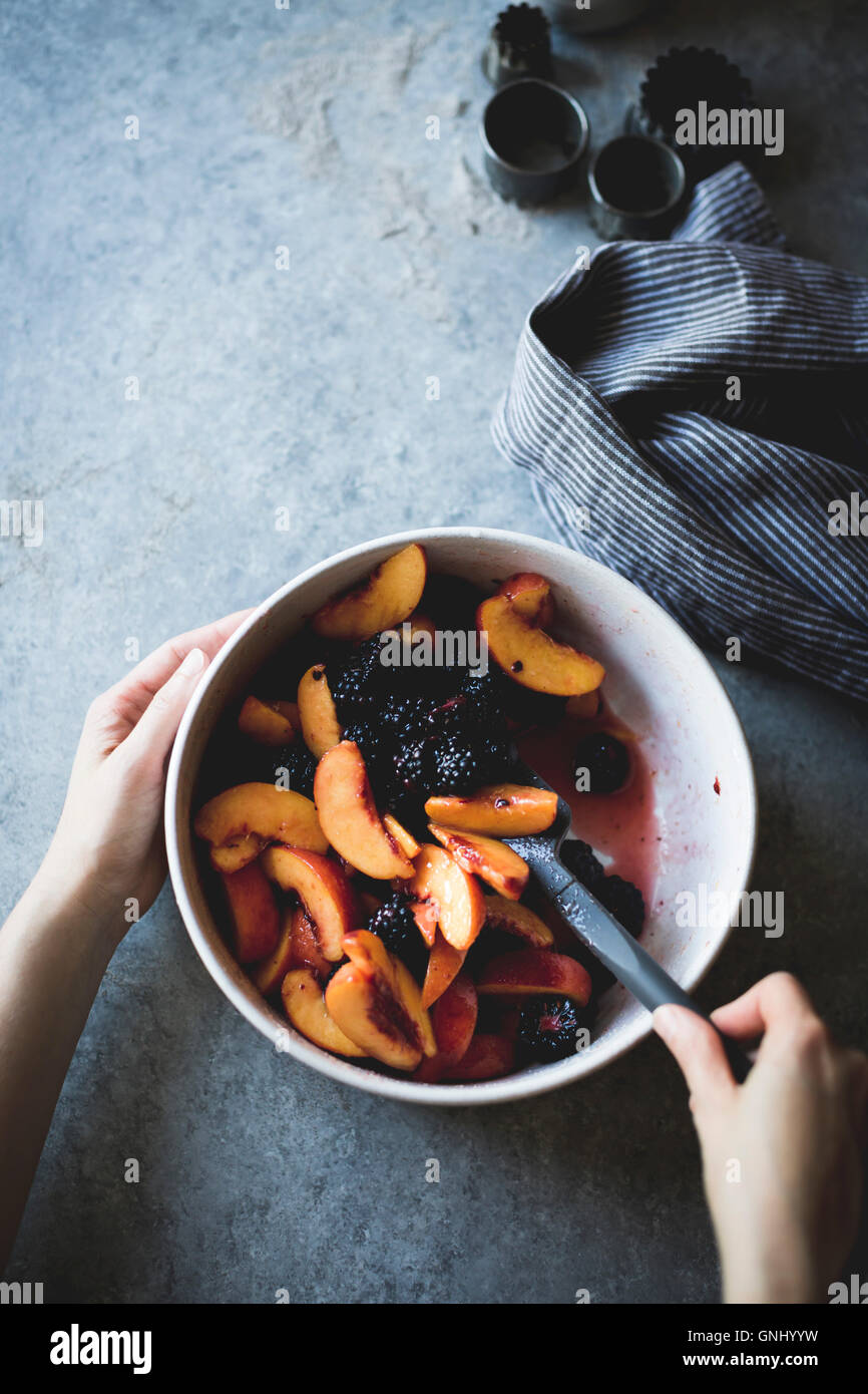 Mixing peaches and blackberries in a mixing bowl Stock Photo