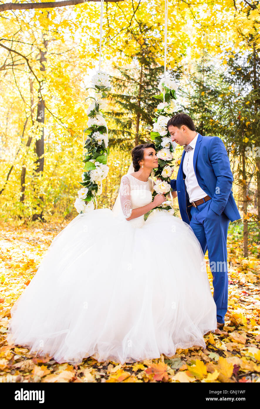 The bride and groom on a swing in autumn park Stock Photo - Alamy