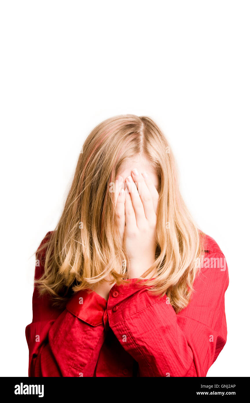 blond tween girl hiding her face behind hands Stock Photo