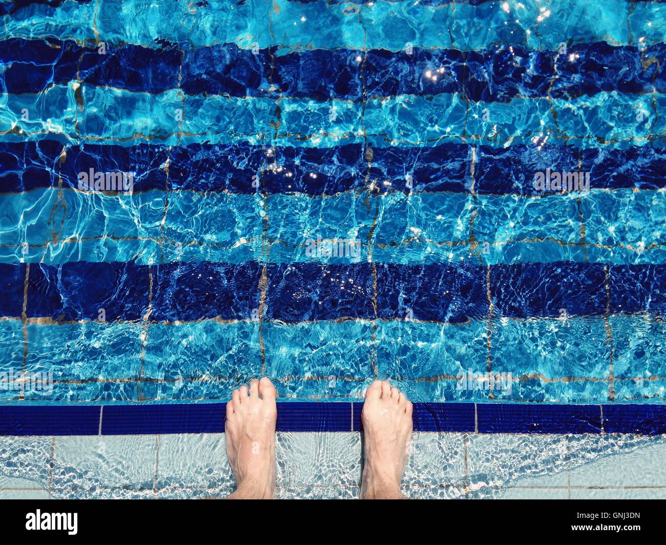 Man's feet standing at the edge of swimming pool Stock Photo - Alamy