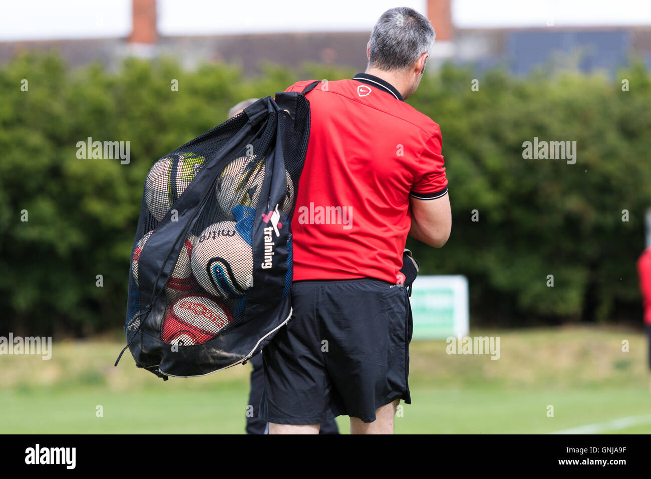 Football coach carrying bag of equipment and balls Stock Photo Alamy
