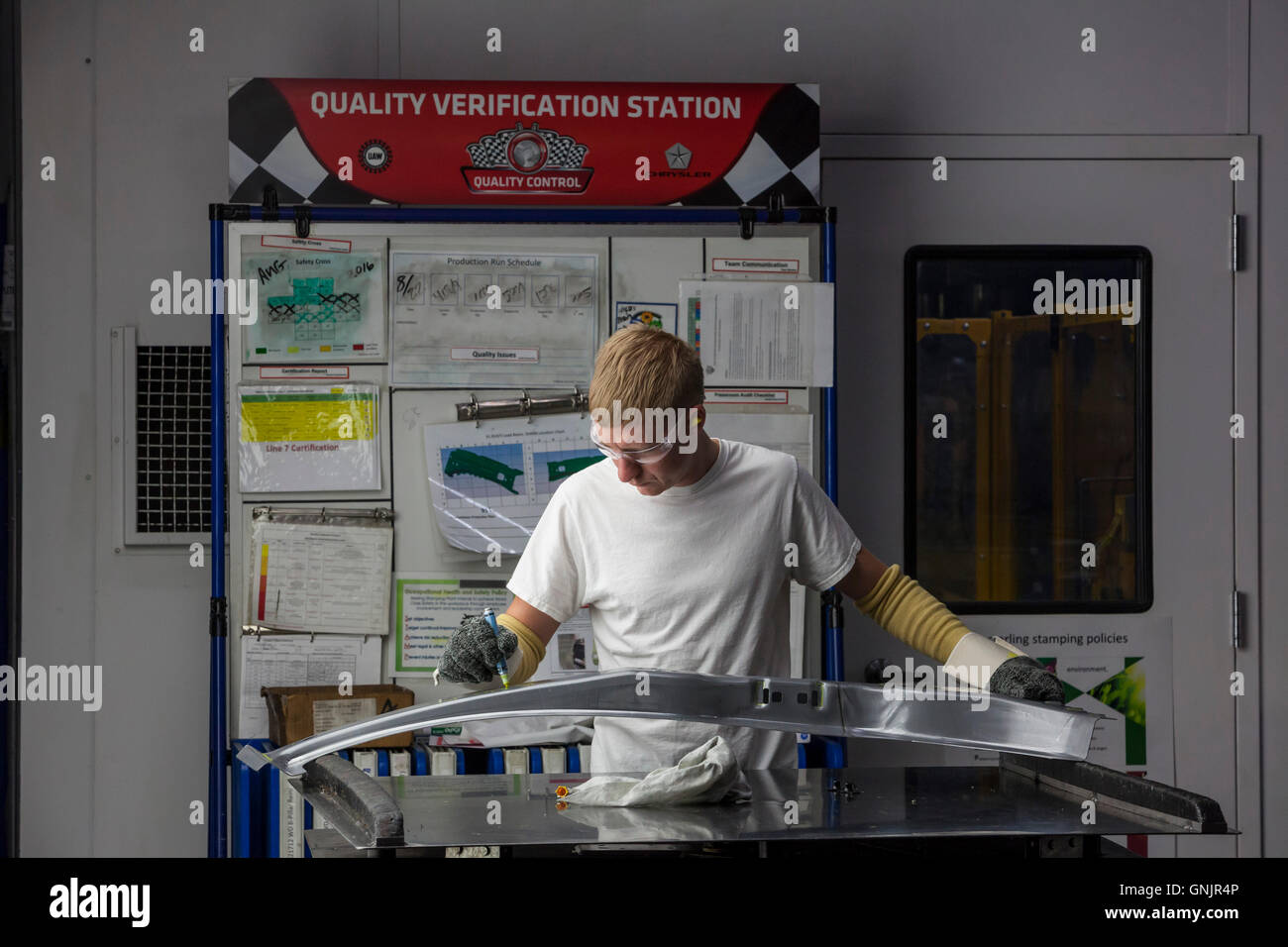 Sterling Heights, Michigan - A worker checks the quality of auto parts emerging from a stamping press. Stock Photo