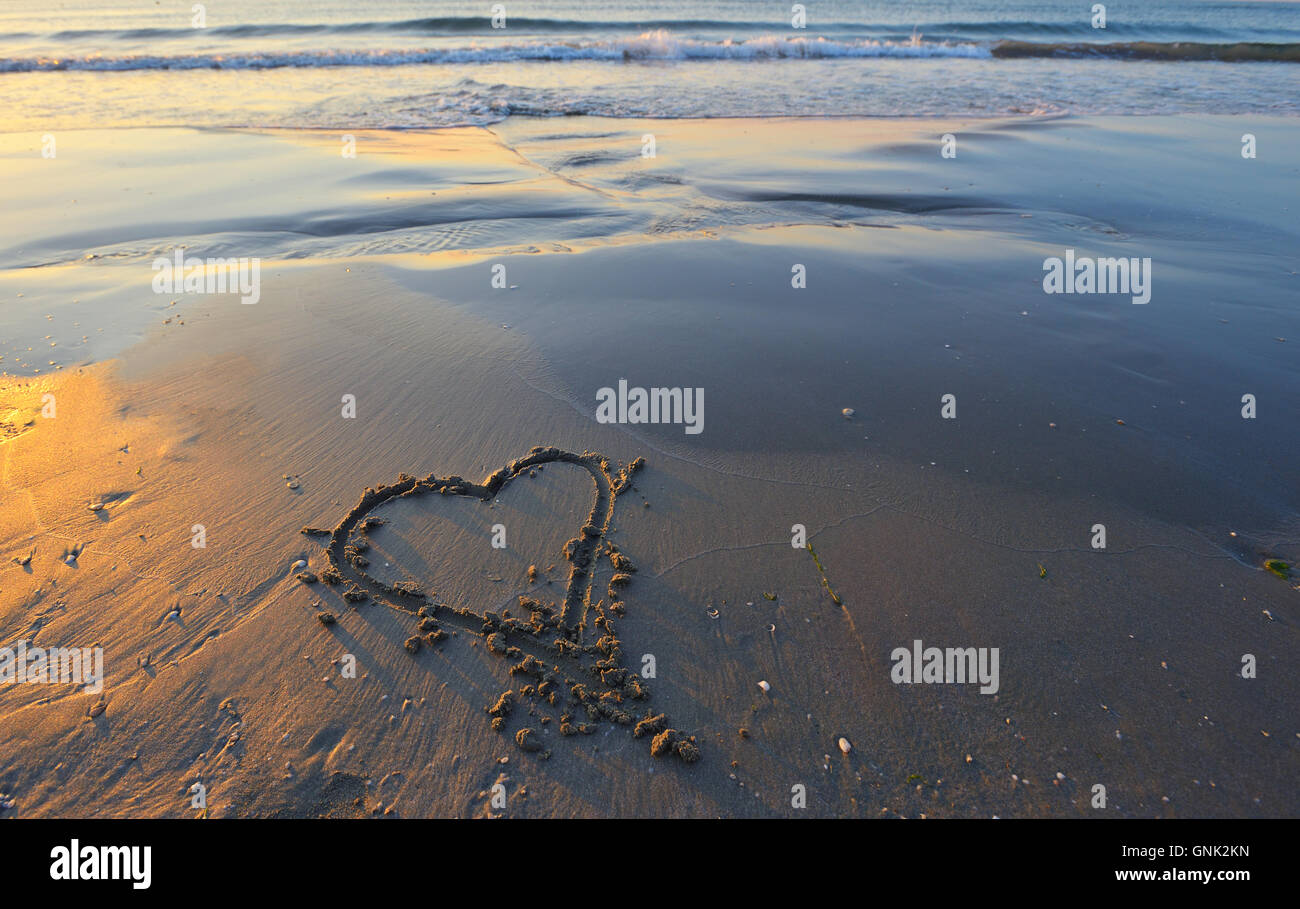 drawing of a heart on a yellow sand at a beautiful seascape background. Stock Photo