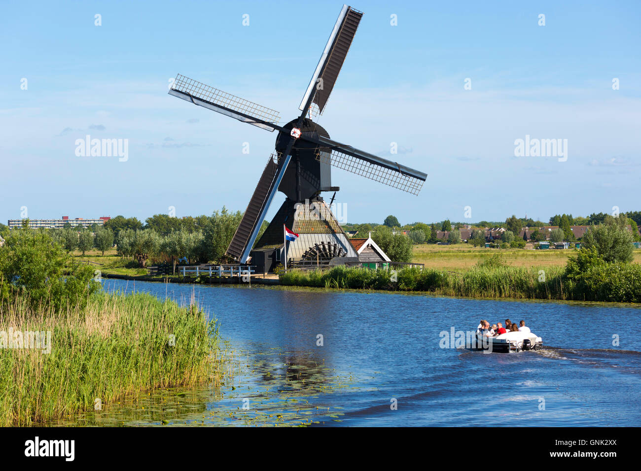 Tourists in boat pass authentic windmill at Kinderdijk UNESCO World Heritage Site, dykes and polder, Holland, The Netherlands Stock Photo