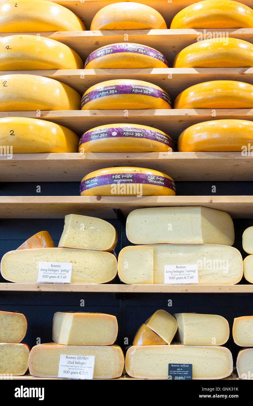 Cheese wheels and wedge on display shelves at traditional cheese shop