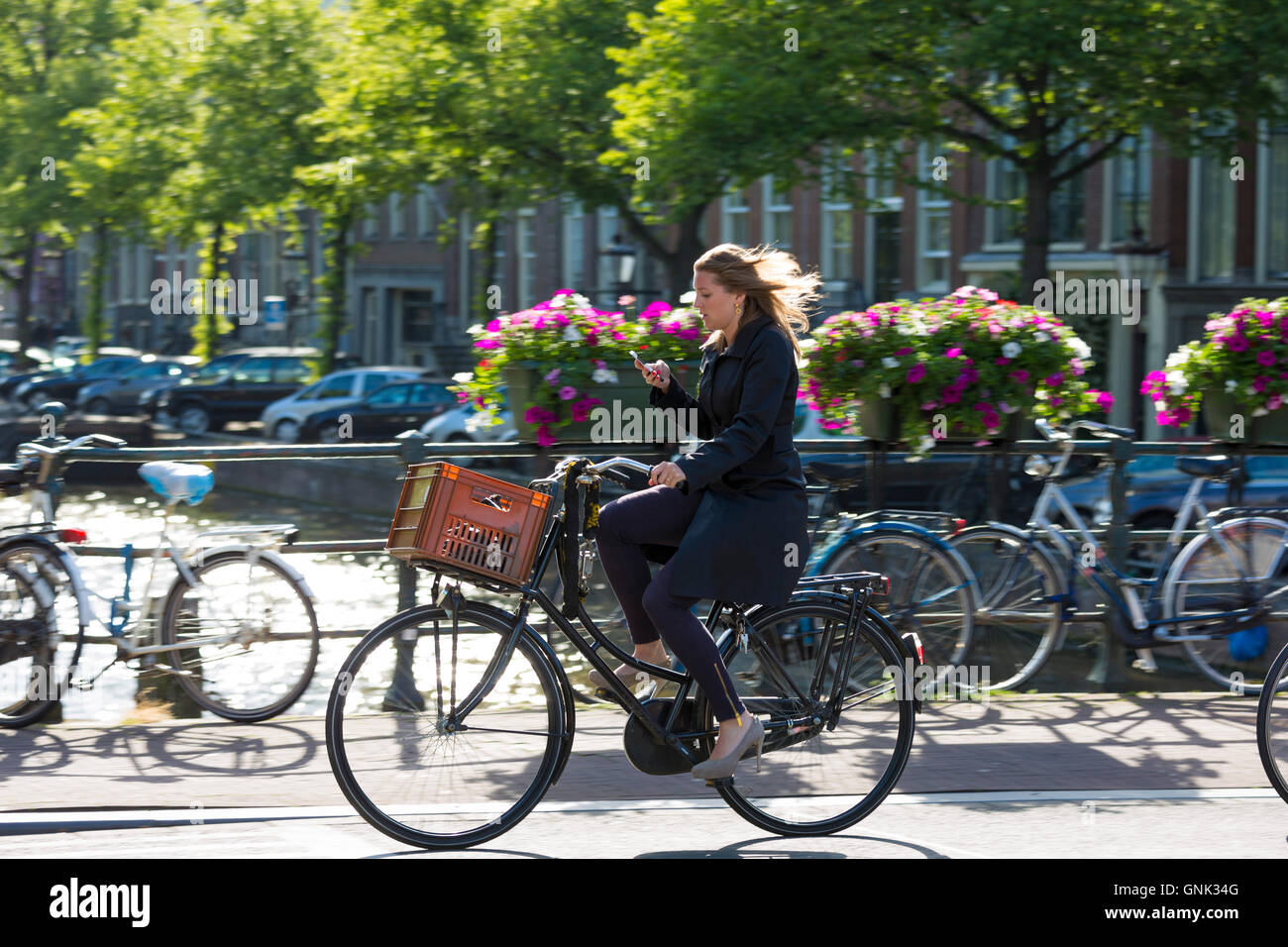 Young woman wearing high heels shoes, carrying iPhone cycling out for the  evening across bridge in Amsterdam, Holland Stock Photo - Alamy