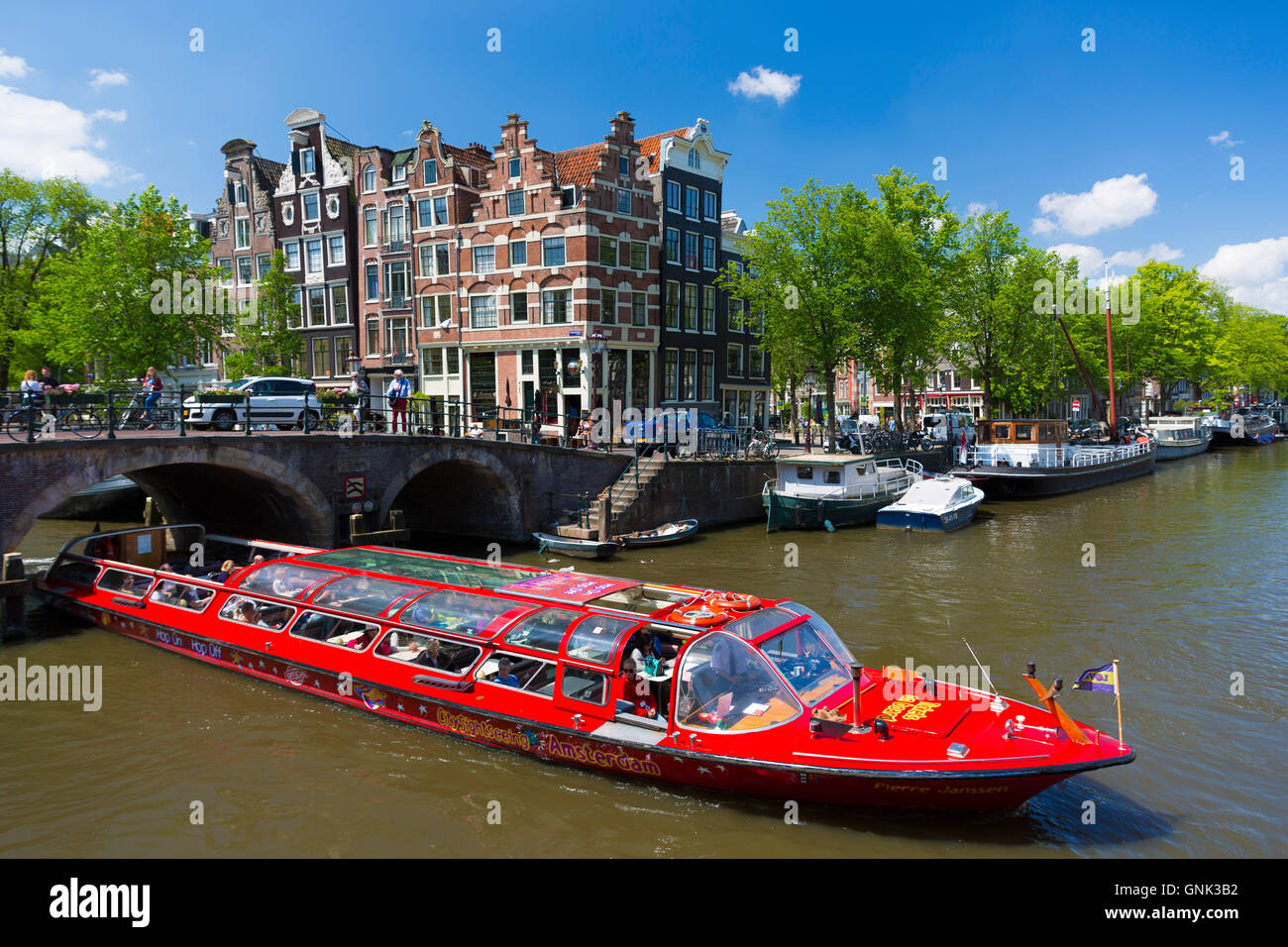 Tourist boat takes tour cruise group sightseeing on Dutch canals, Prinsengracht and Brouwersgracht, Amsterdam, Holland Stock Photo