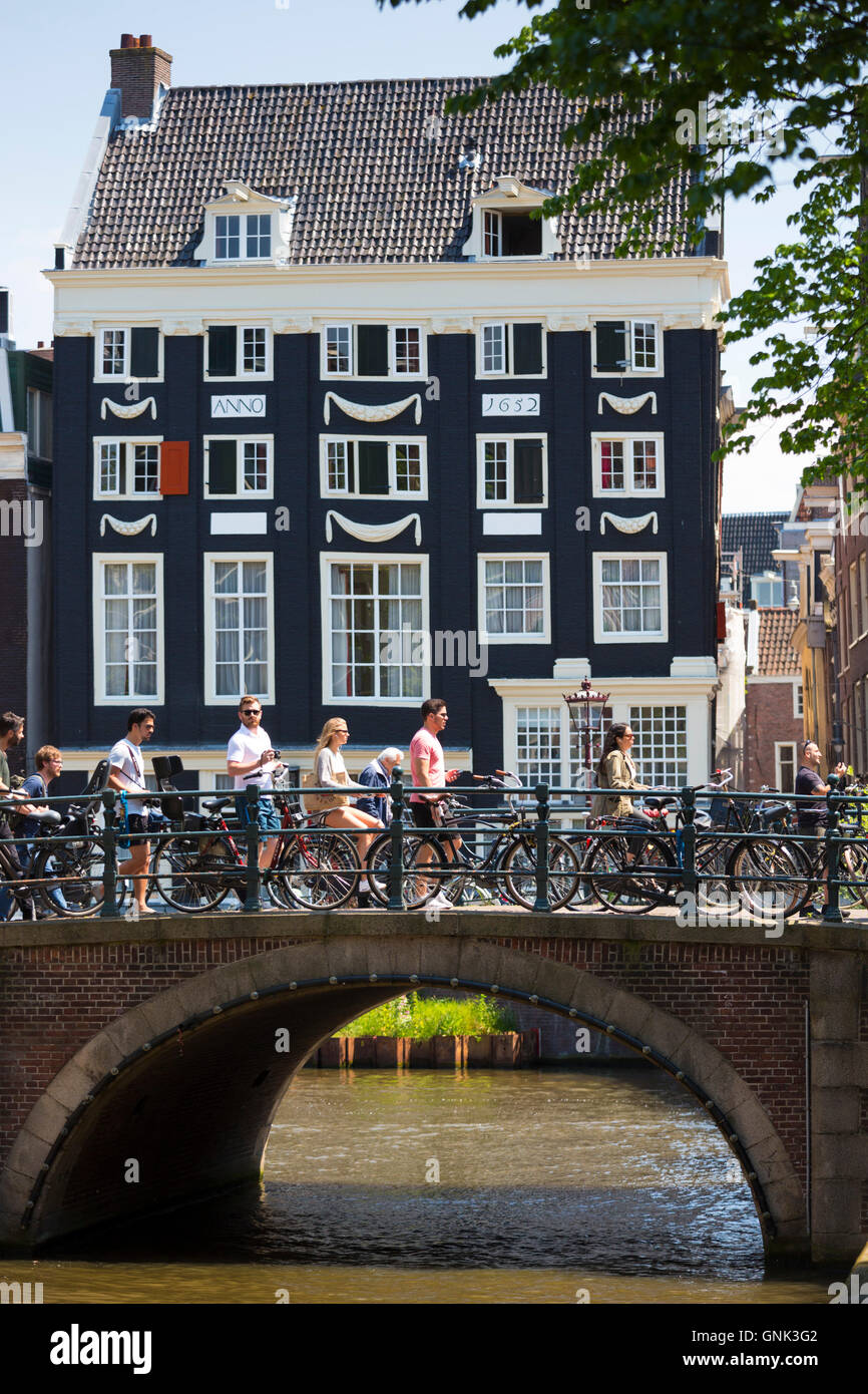 Canalside cyclists house and bridge at Herengracht / Singel in Jordaan District of Amsterdam, Holland Stock Photo