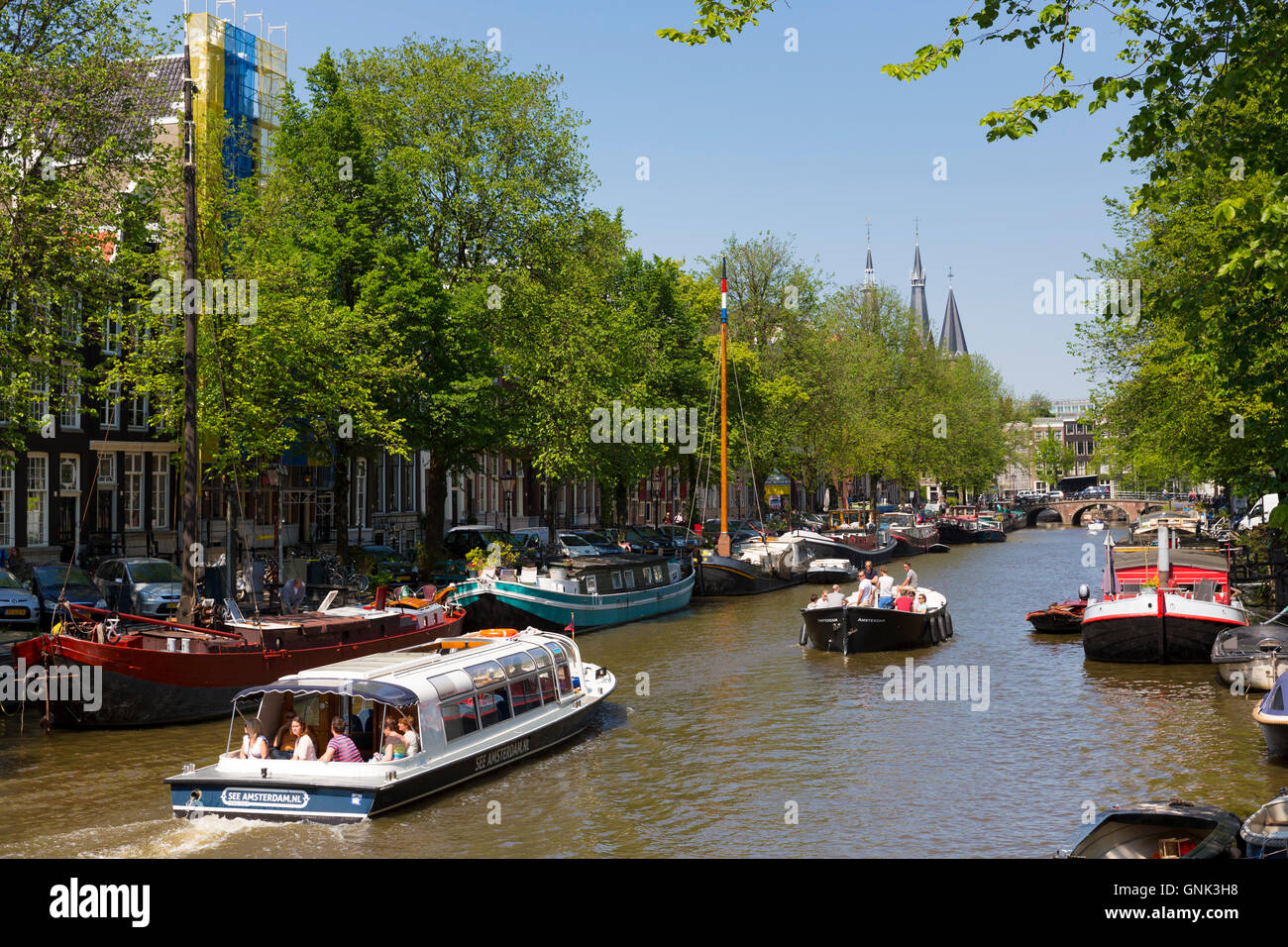 Tourist boat on sightseeing cruise tour along the canal district in the Jordaan area of Amsterdam, The Netherlands Stock Photo