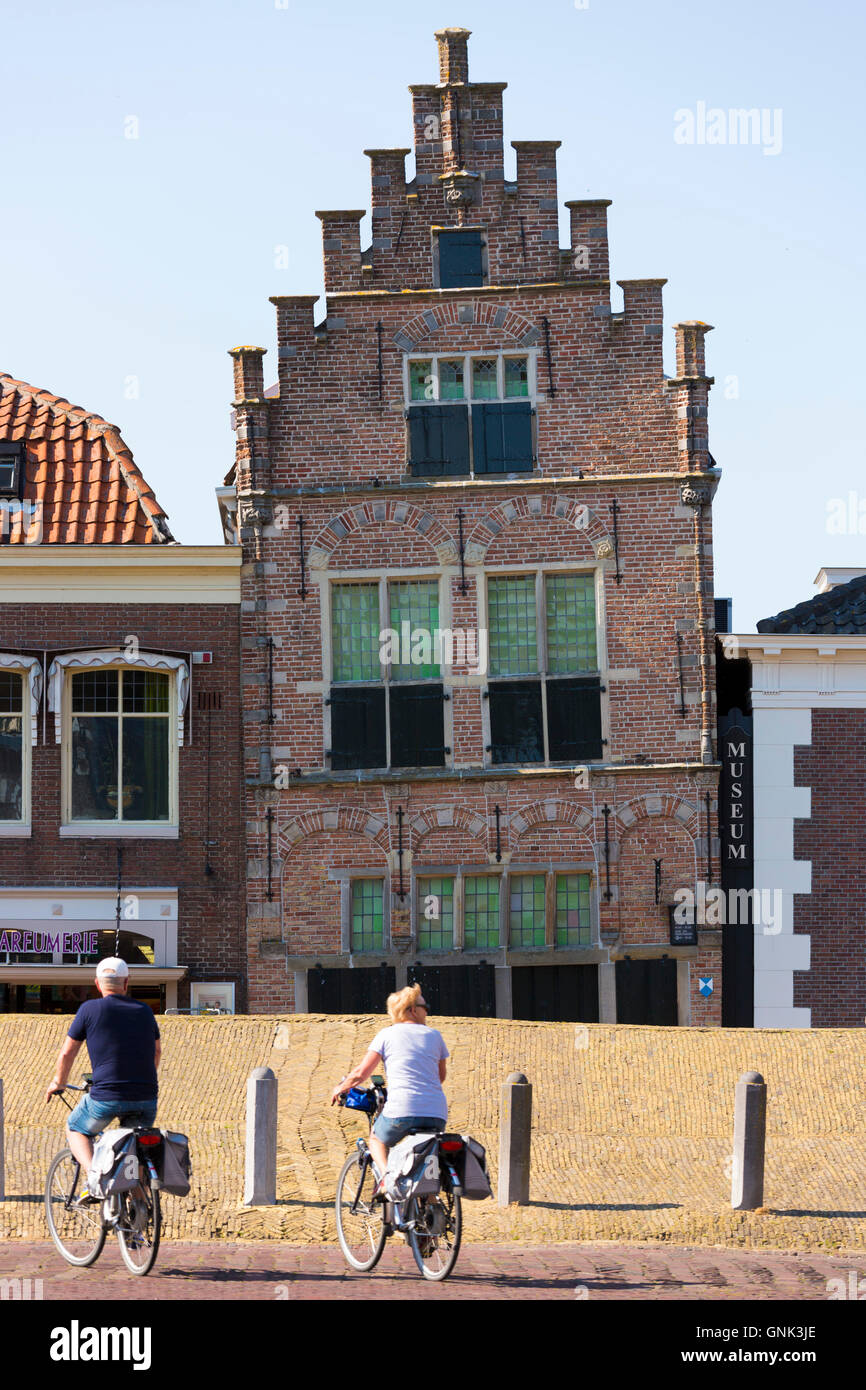 Cyclists and traditional architecture lopsided ancient building of theTown Hall Museum, Edam, The Netherlands Stock Photo