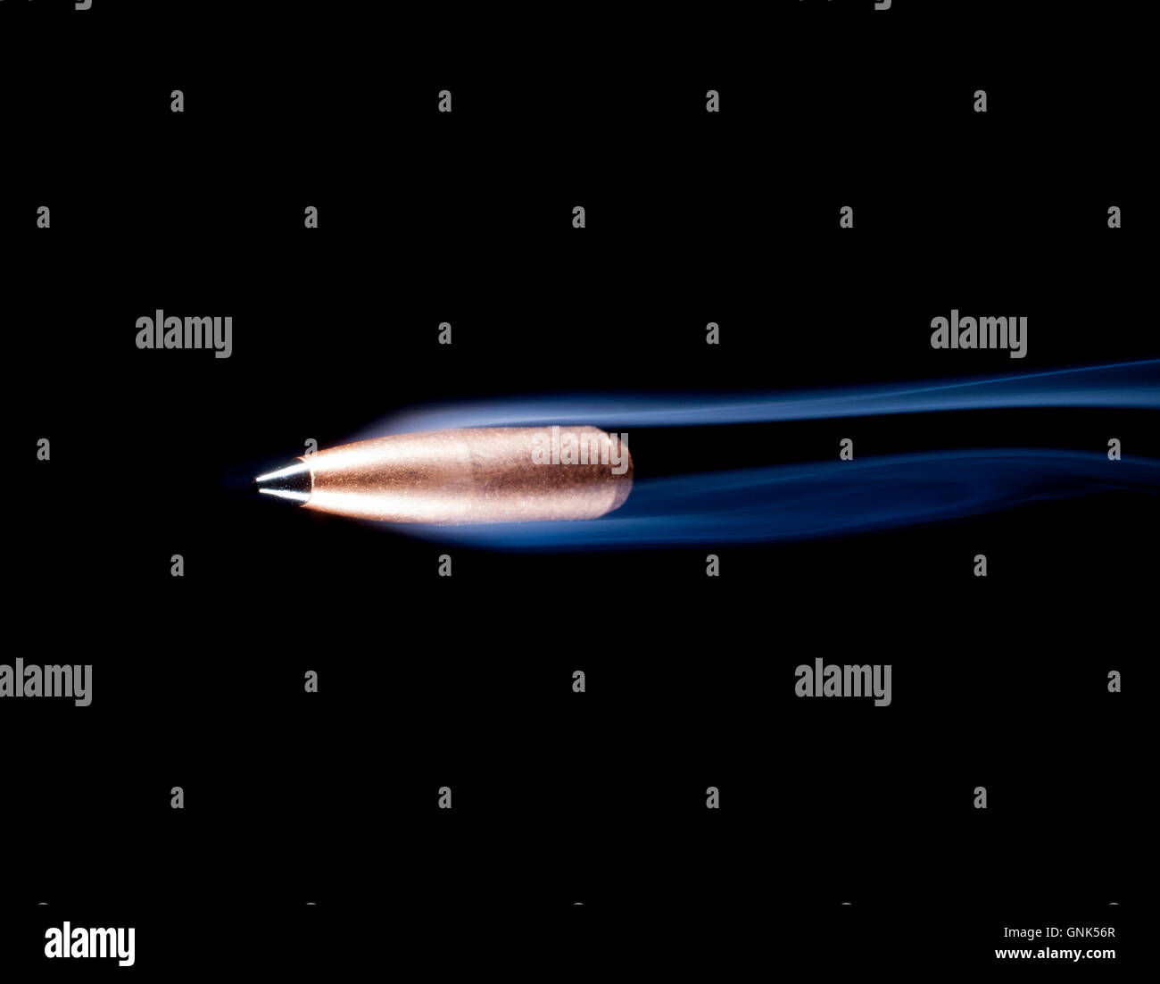 Copper plated lead bullet with a black polymer tip and smoke behind Stock Photo Alamy