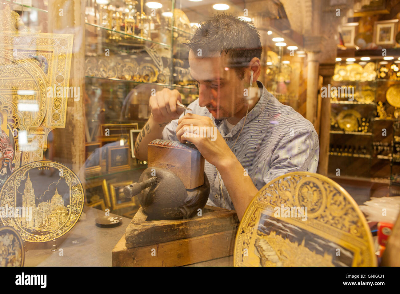 Toledo, Spain - July 28, 2016: goldsmith working on damascening piece through the shop window in historic center of Toledo, Spai Stock Photo