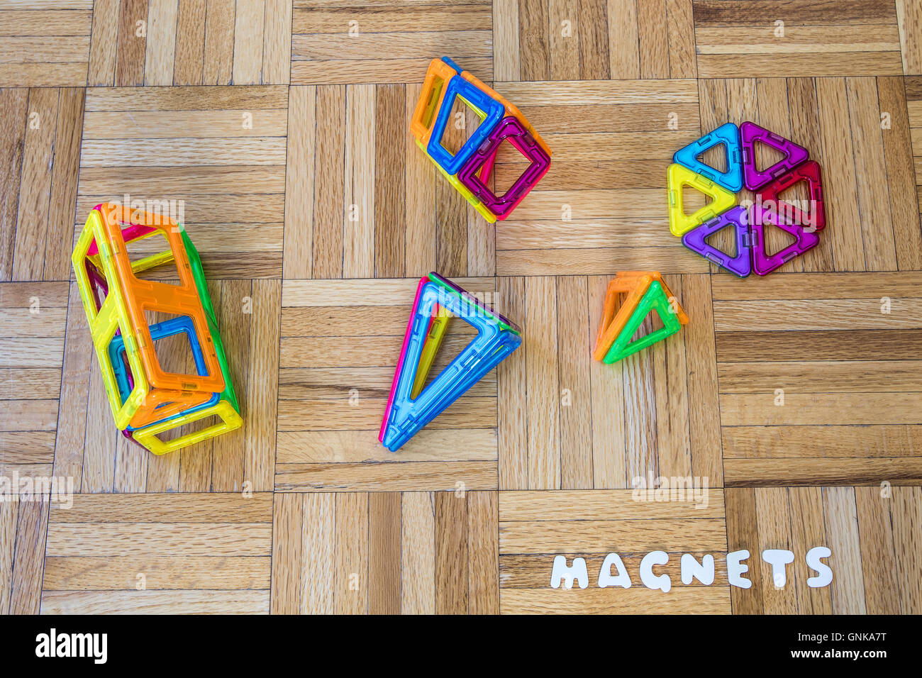 Toy magnets on a parquet floor. Stock Photo