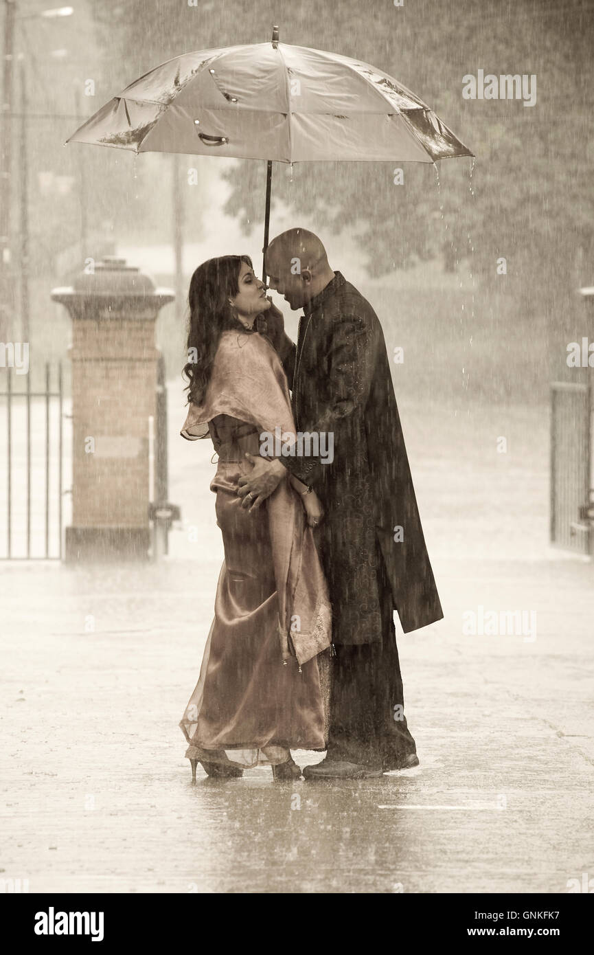 Indian smartly dressed couple holding an umbrella in the rain Stock ...