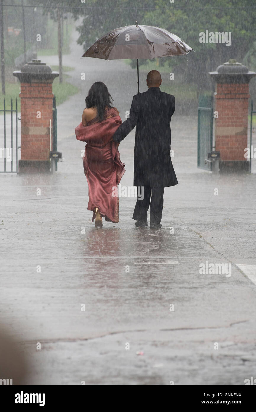 Indian smartly dressed couple holding an umbrella in the rain Stock ...
