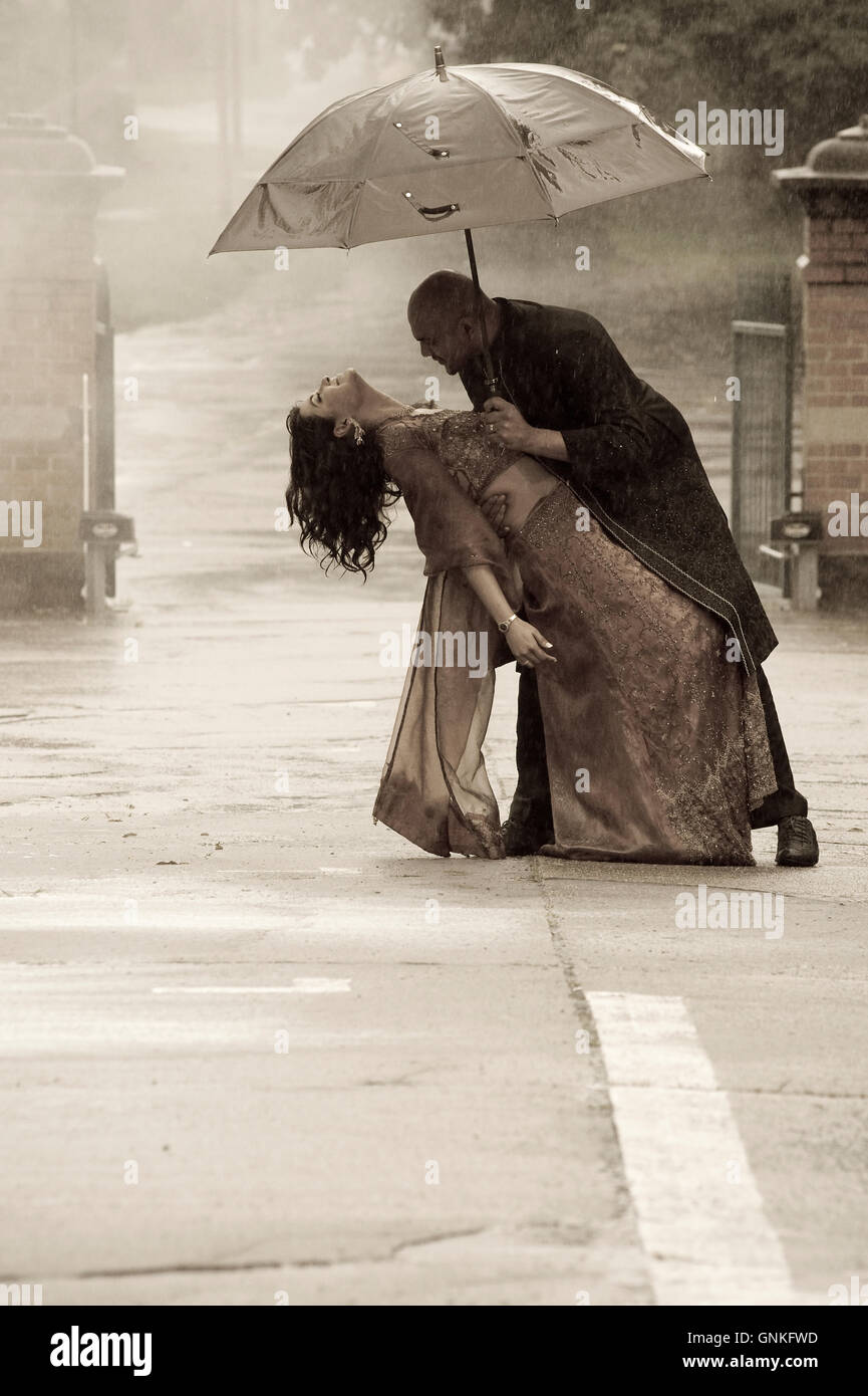 Indian smartly dressed couple holding an umbrella in the rain Stock ...
