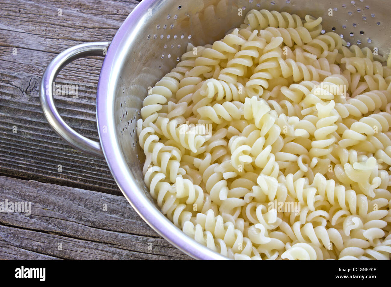 Fresh cooked fusilli pasta in strainer on table Stock Photo
