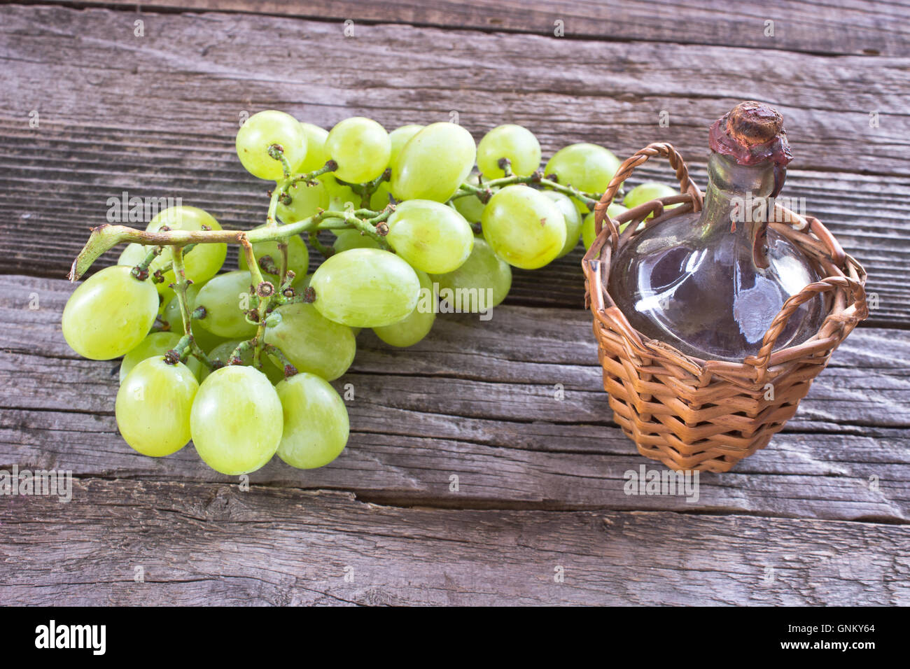 Old sealed bottle of wine and white grape on wooden background Stock Photo