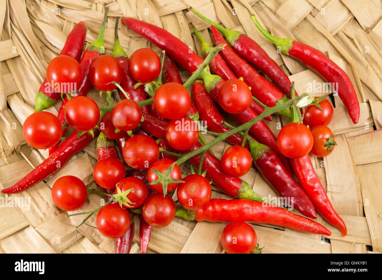 Red peppers and fresh cherry tomato on wooden background Stock Photo