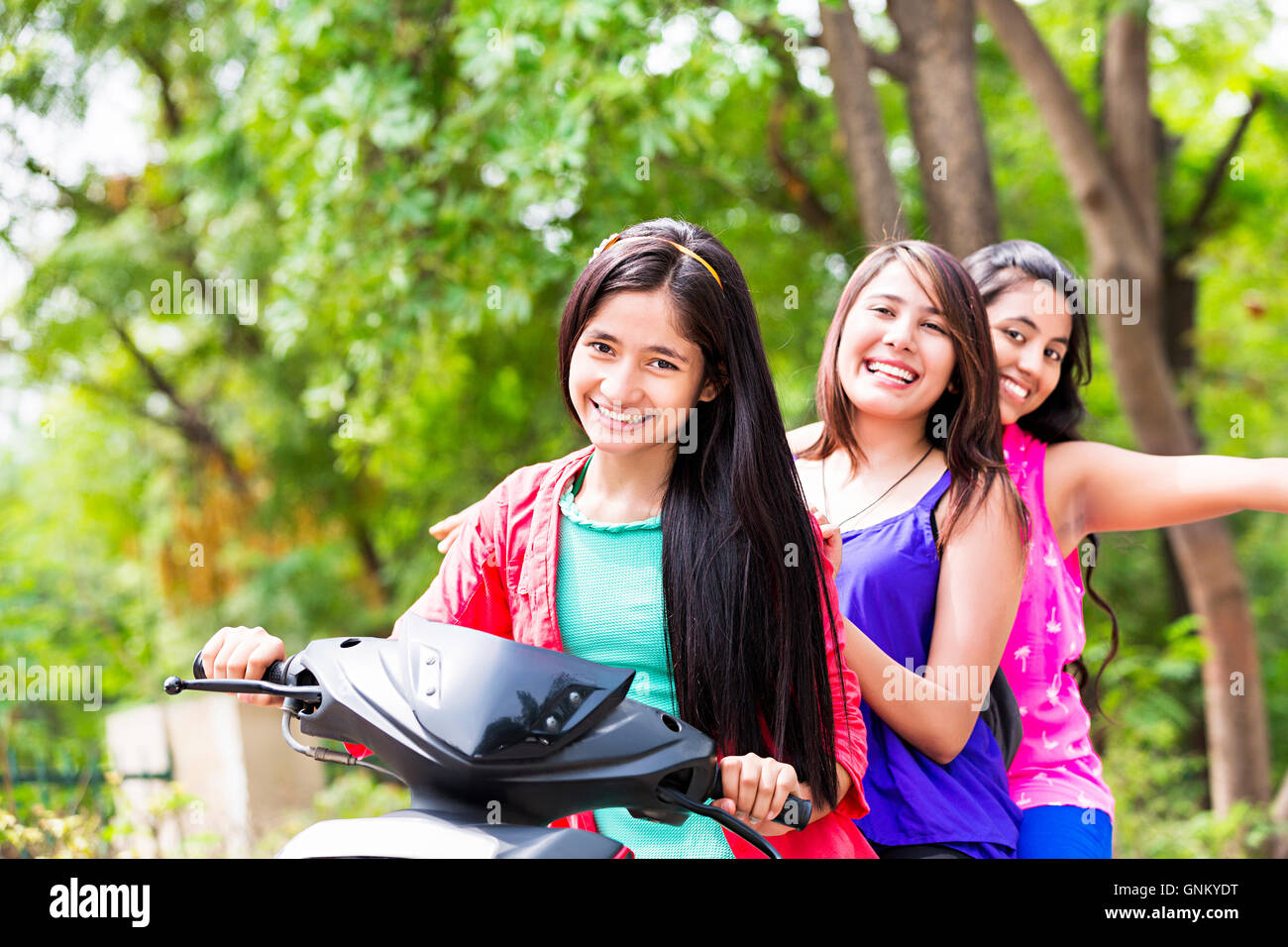 3 Young Girls Friends Park Riding Scooty enjoy Stock Photo
