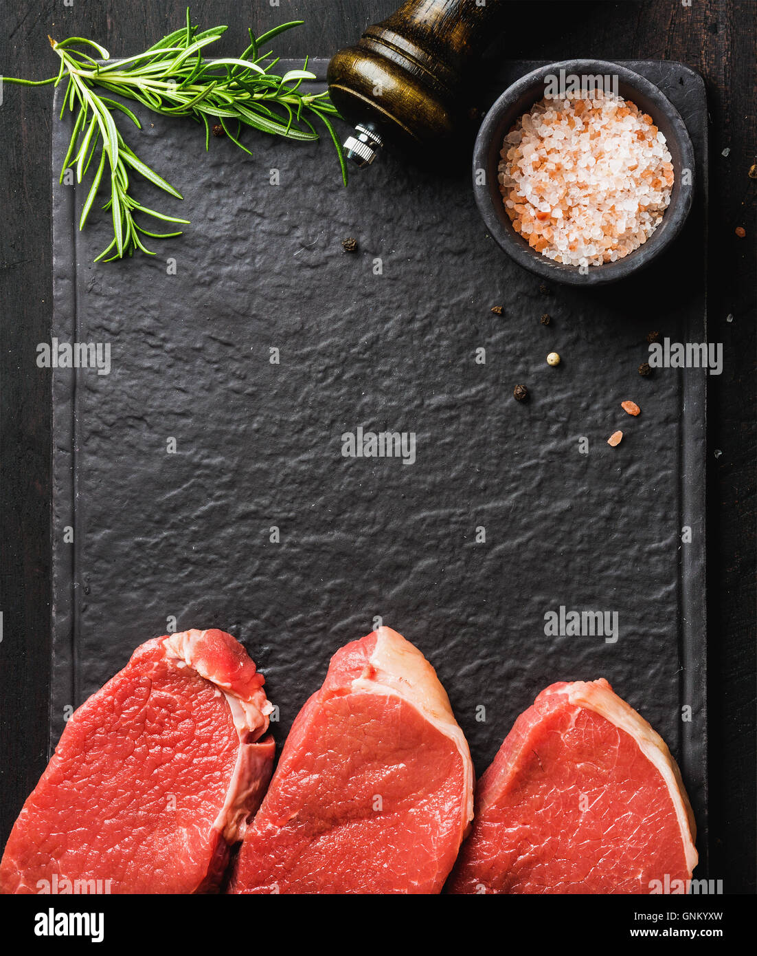 Raw beef Eye Round steaks with spices, rosemary. Copy space Stock Photo