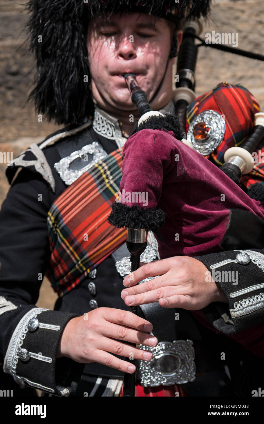 Detail of man playing bagpipes for tourists wearing traditional military uniform with tartan and kilt in Edinburgh, Scotland Stock Photo