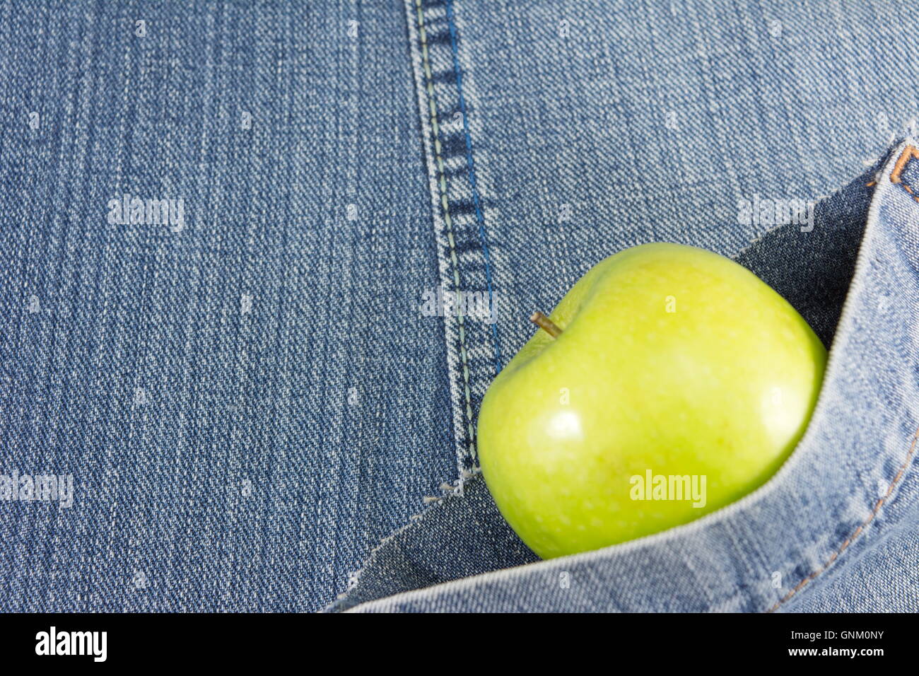Green apple in denim blue jeans pocket Stock Photo