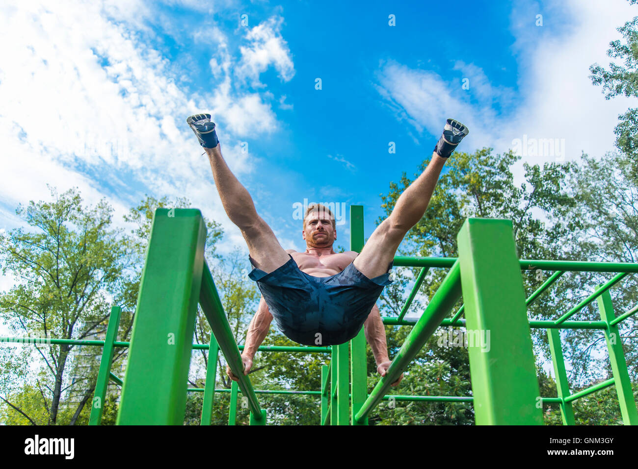 Young man doing pull ups on horizontal bar outdoors Stock Photo - Alamy