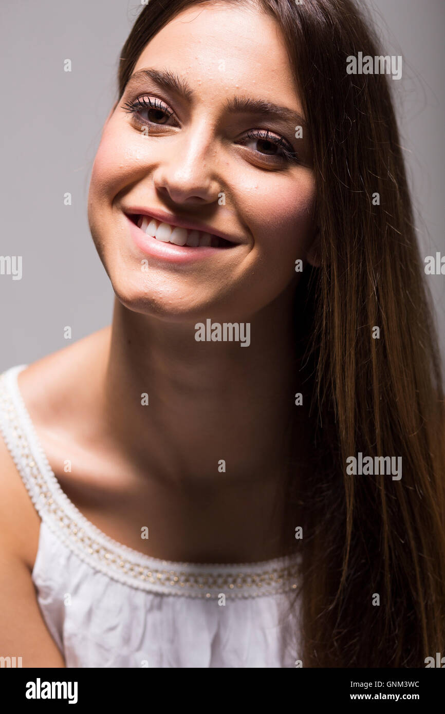 Pretty young woman with long hair in white dress in studio Stock Photo