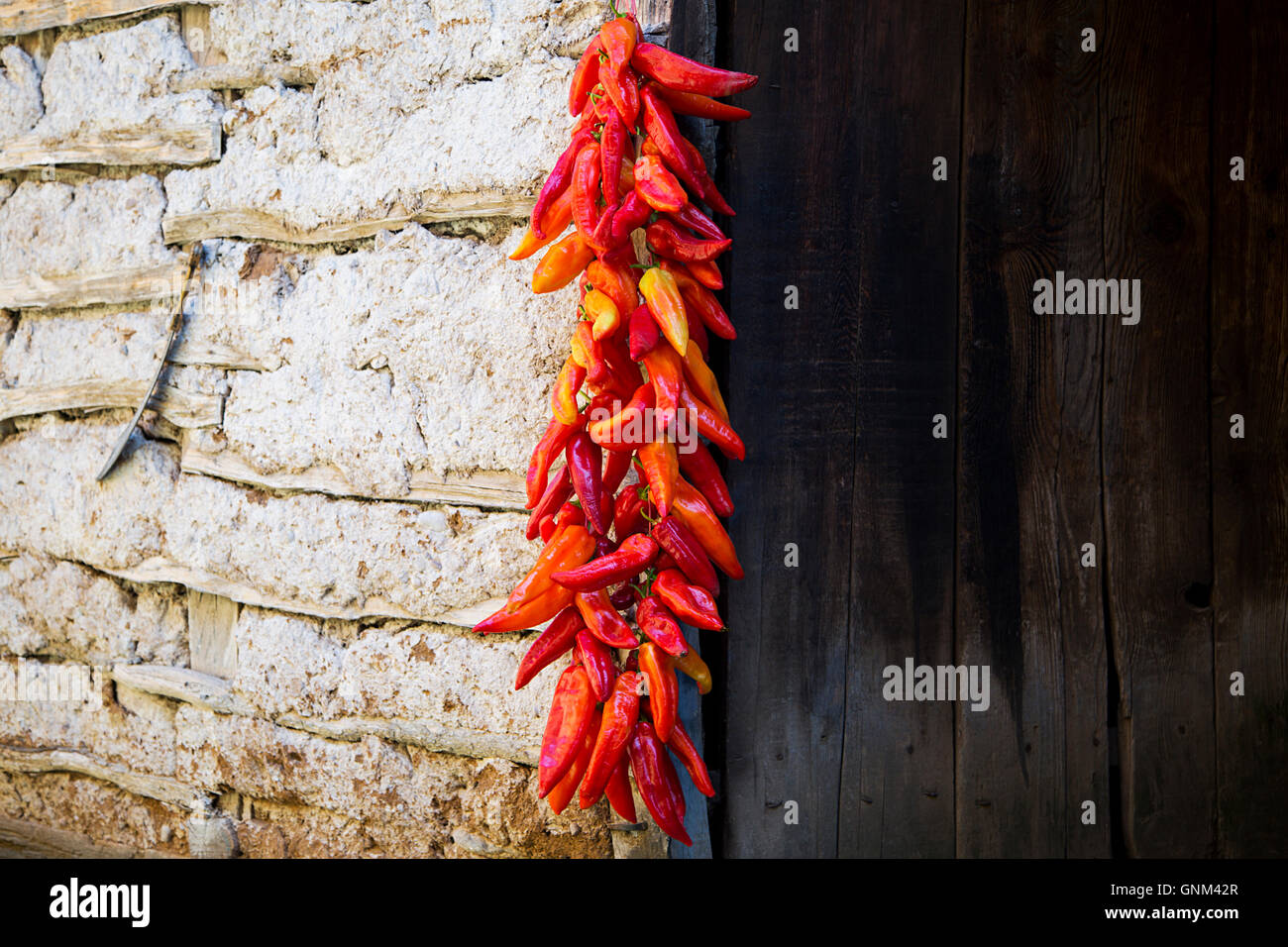 Red Paprika Peppers traditionally hanging To Dry On The Wall Of A House Stock Photo