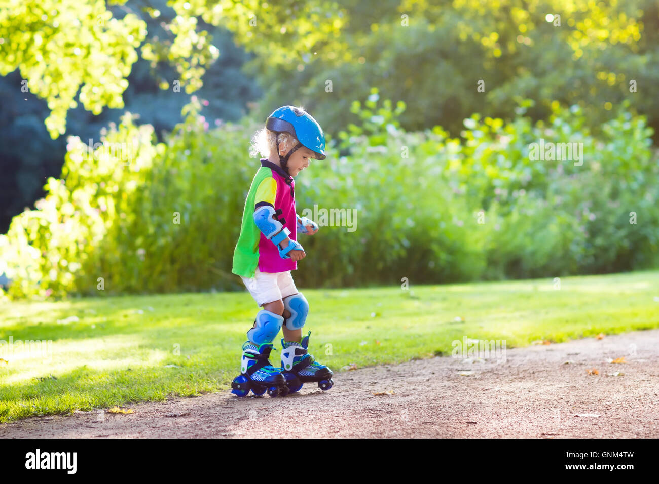 Little girl learning to roller skate in sunny summer park. Child